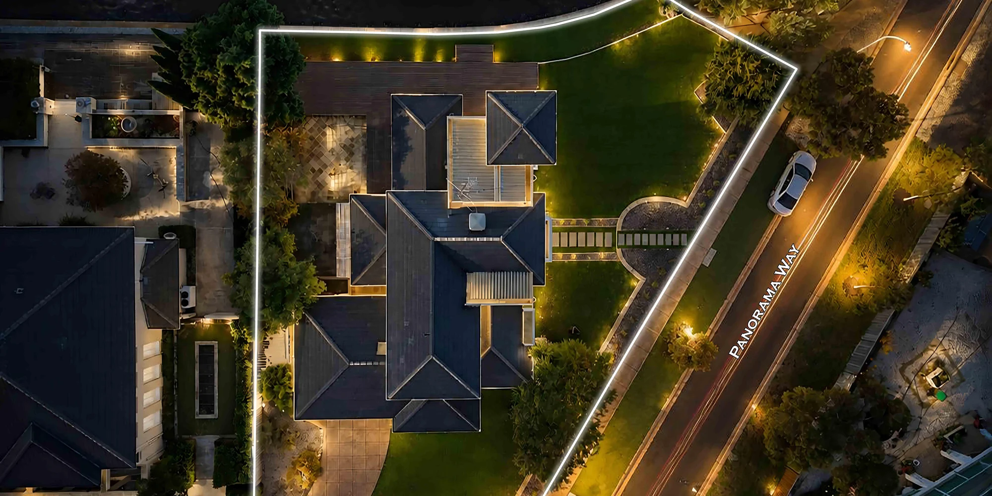Dusk aerial photograph of a Melbourne home, its grounds and boundary traced in light from four hundred feet